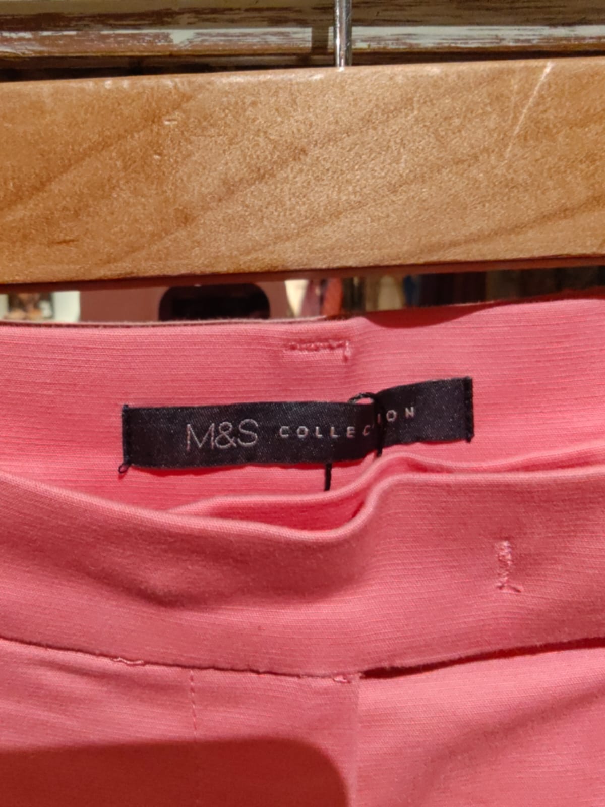 Close-up of a pink garment with an M&S Collection label on a wooden surface.